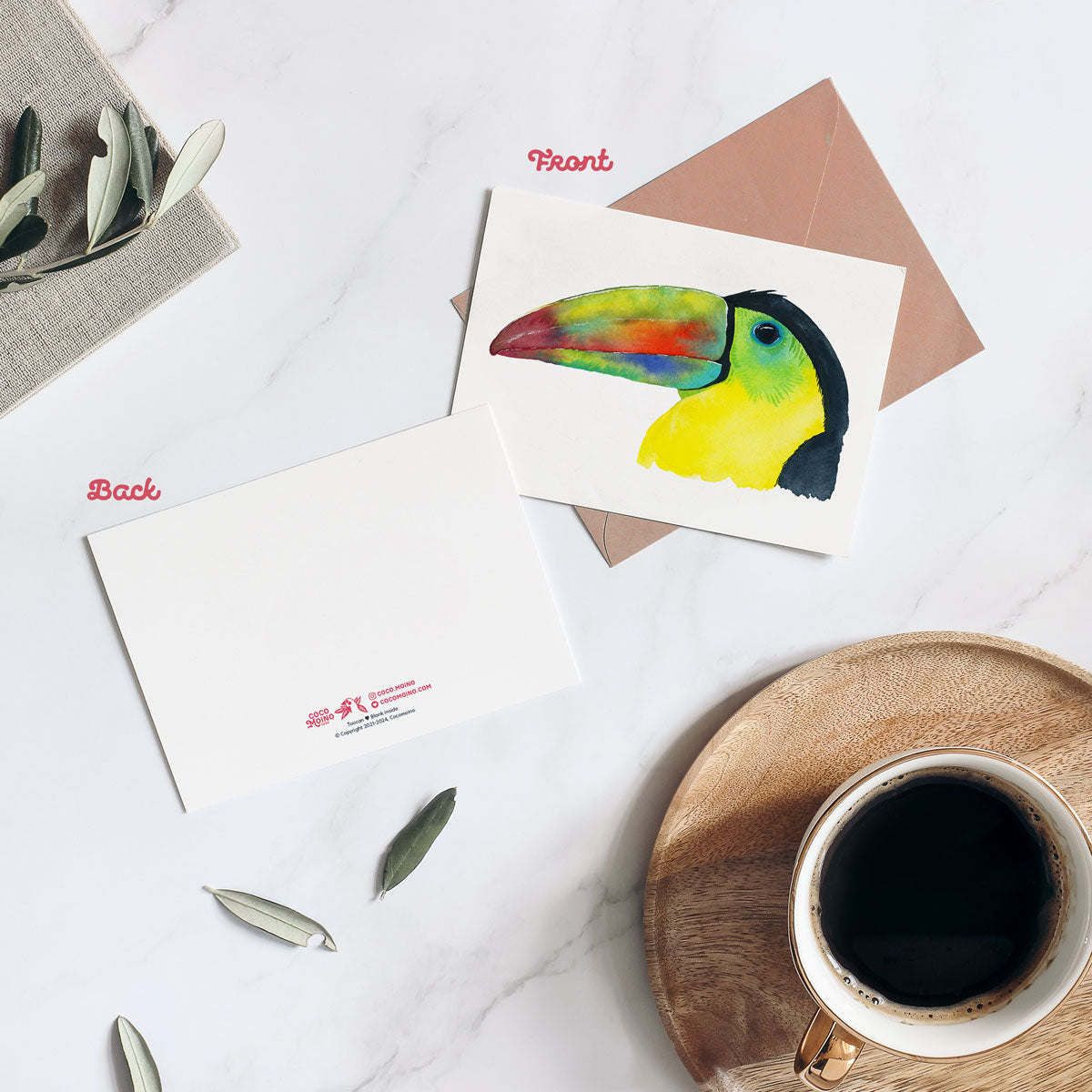 Watercolor toucan greeting card displayed on a marmor table with coffee and envelope
